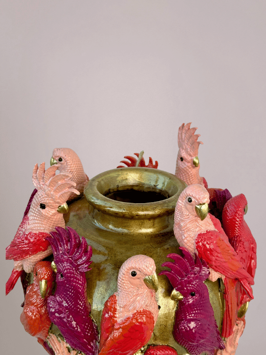 Bovenaanzicht van gouden vaas met smal gat en kleurrijke kaketoevogels rondom de rand.