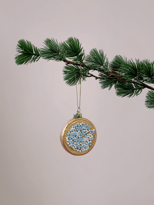 Vondels beschuit met muisjes kerstbal met glitter in blauw en wit hangend in een kerstboom.