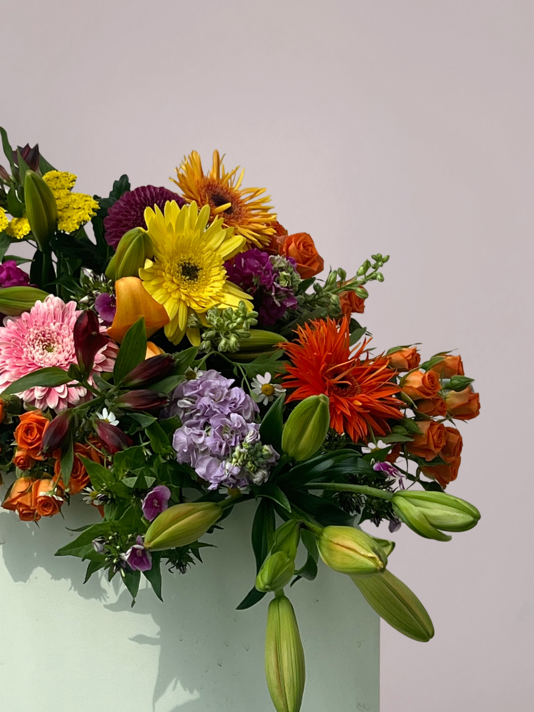 Kleurrijk rouwboeket met gemengde bloemen in roze, geel, paars en oranje tinten