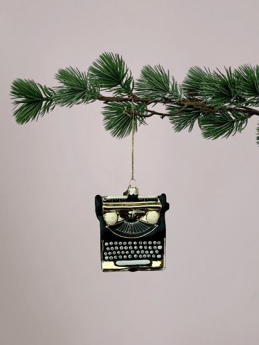 Vondels zwarte typemachine kerstbal met gouden details hangend in een kerstboom.