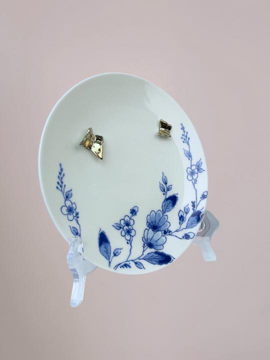 Delfts blauw wandbord van Heinen met blauwe bloemen langs de rand en 3D gouden vlinders op wit keramiek