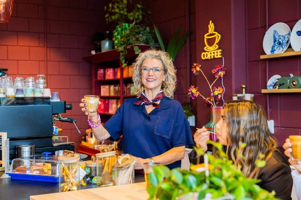 Anja van Anja Bloementrends lacht en houdt koffie vast in haar bloemenwinkel koffiecorner in Zwolle Stadshagen