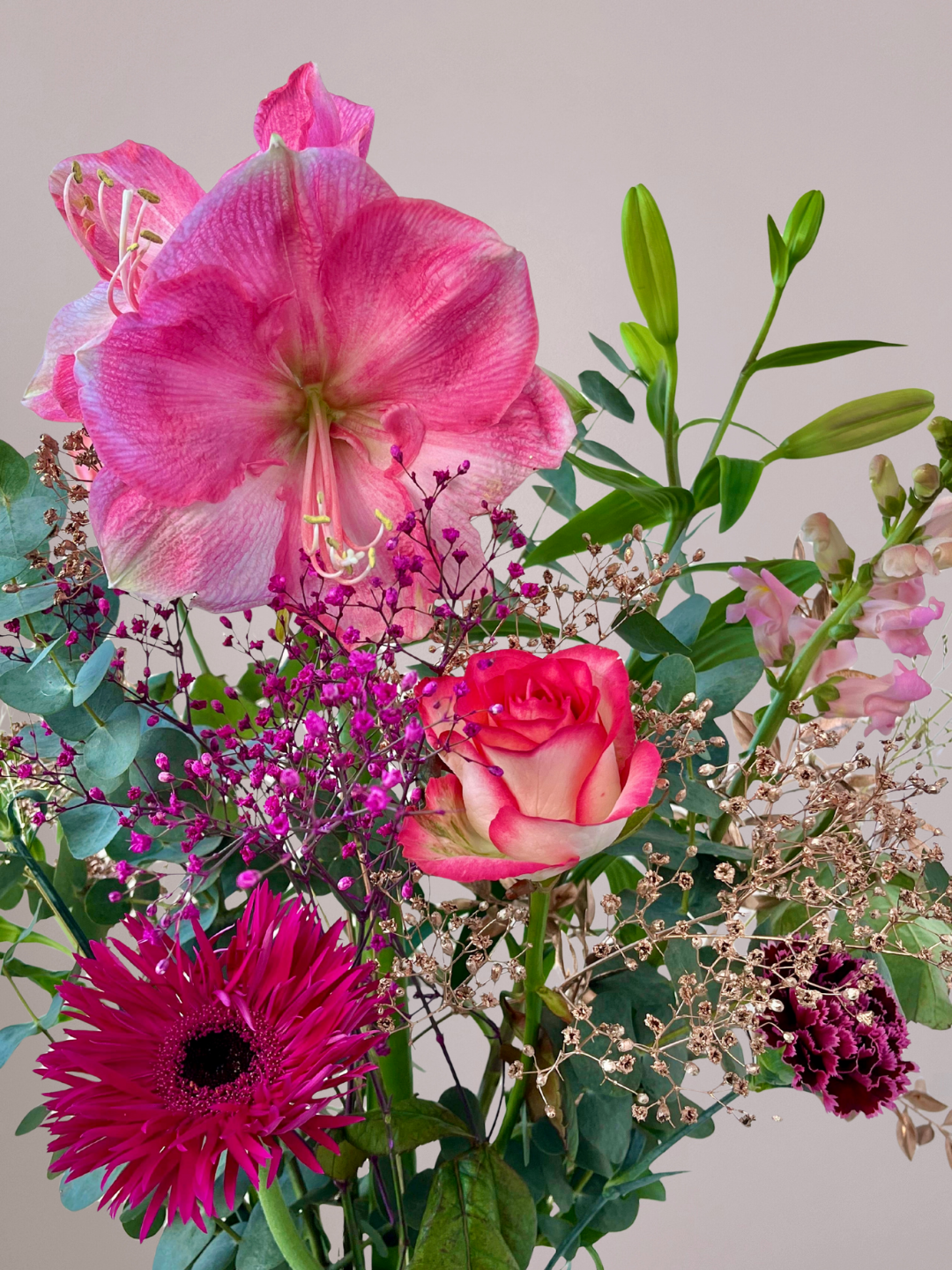 Close-up van roze kerstbloemen met zachte wintergroen accenten bij Anja Bloementrends