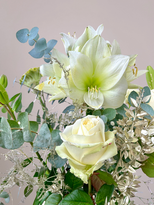 Detailshot van witte en gouden kerstbloemen met natuurlijke groene accenten, bloemen bezorgen Zwolle