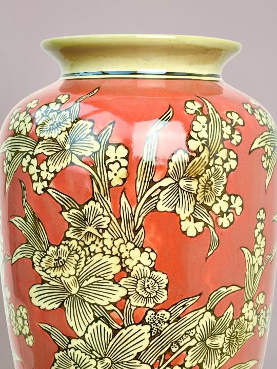 detail van rode vaas met handgeschilderde bloemen en fijne zwarte lijnen