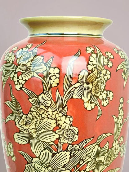 detail van rode vaas met handgeschilderde bloemen en fijne zwarte lijnen