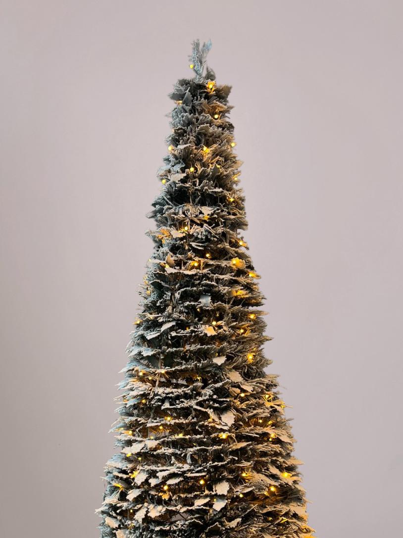 Close-up van warm-witte lampjes van de pop up kerstboom met sneeuw in het donker voor een sfeervolle kerstgloed.