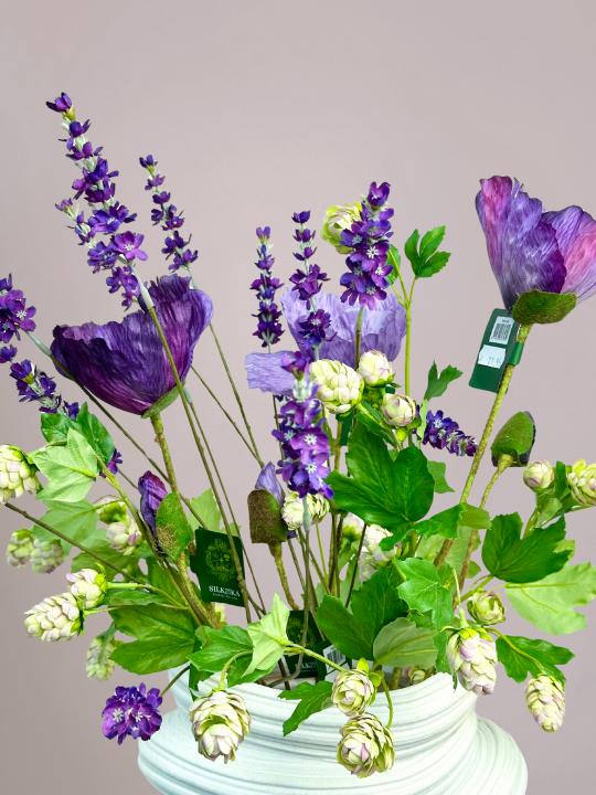 detail van paarse kunstbloemen en zijden bloemen in grote vaas met klaprozen en lavendel