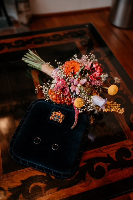 Op houten tafel liggen trouwringen met bruidsboeket in kleur van Anja Bloementrends in Zwolle Stadshagen