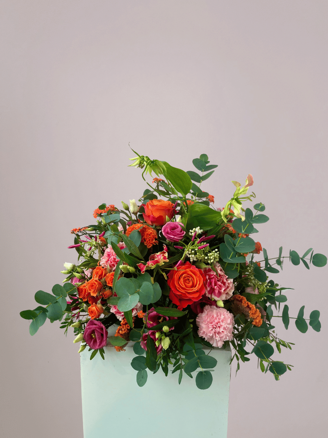 Gekleurd rouwboeket met warme rood-, oranje- en rozetinten, handgebonden in Zwolle als persoonlijk en liefdevol afscheid.