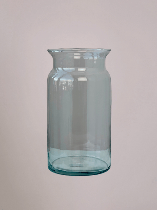 Cilindervormige glazen vaas met roze achtergrond