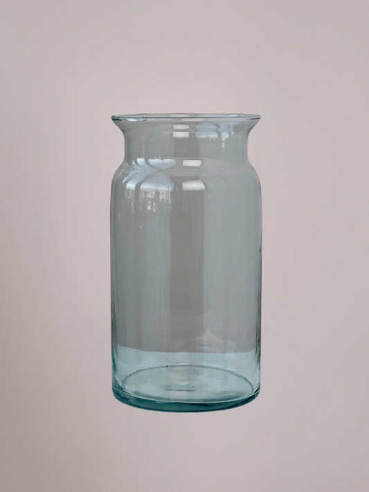 Cilindervormige glazen vaas met roze achtergrond