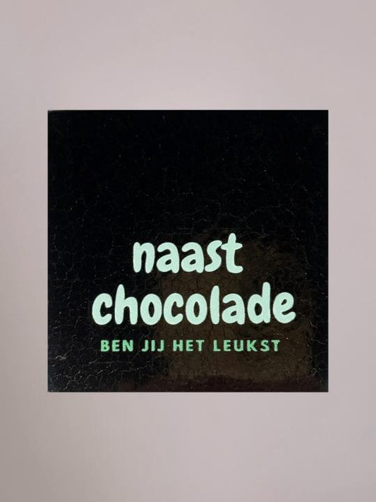 Goudkleurig keramieken tegeltje met lichtblauwe tekst “naast chocolade” en mintgroene tekst “ben jij het leukst”