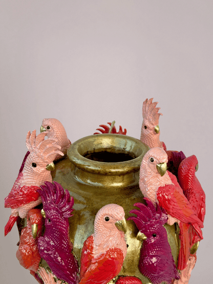 Bovenaanzicht van gouden vaas met smal gat en kleurrijke kaketoevogels rondom de rand.