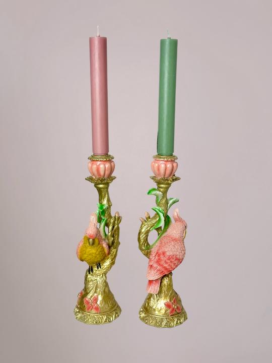 Gouden kandelaar met vogel in de vorm of detail van een lichtroze kaketoe en lichtgroene accenten, volledig in beeld weergegeven.