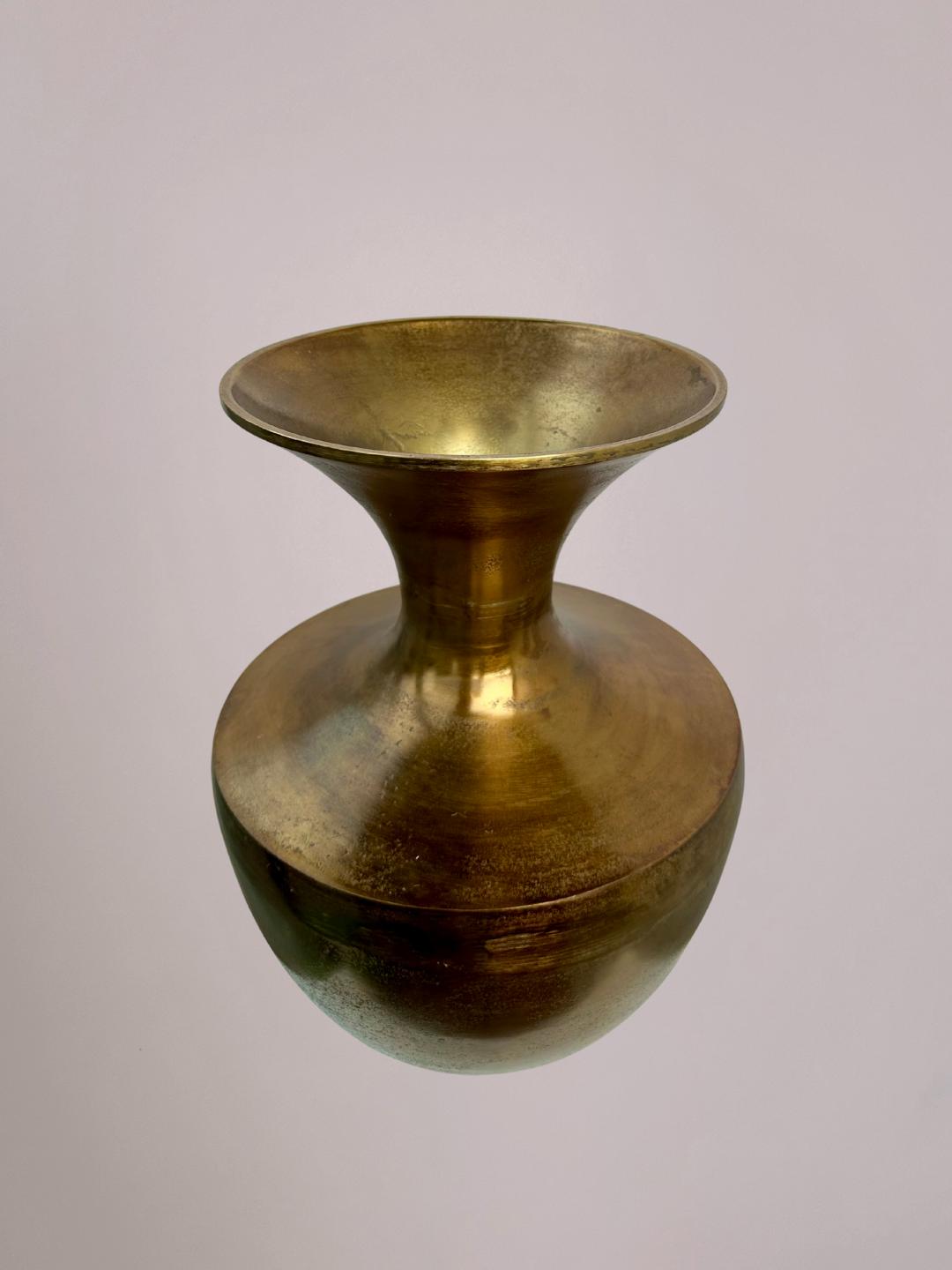 Foto van bovenaf grote gouden vaas met ronde opening en lichtroze achtergrond