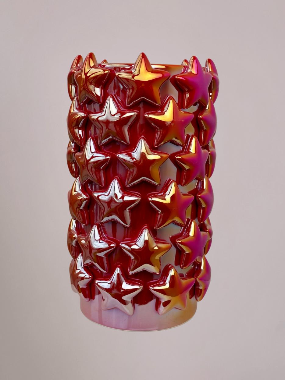 Grote rode vaas van opzij, glimmend holografisch effect verandert van roze naar goud en zilver, sterren zichtbaar