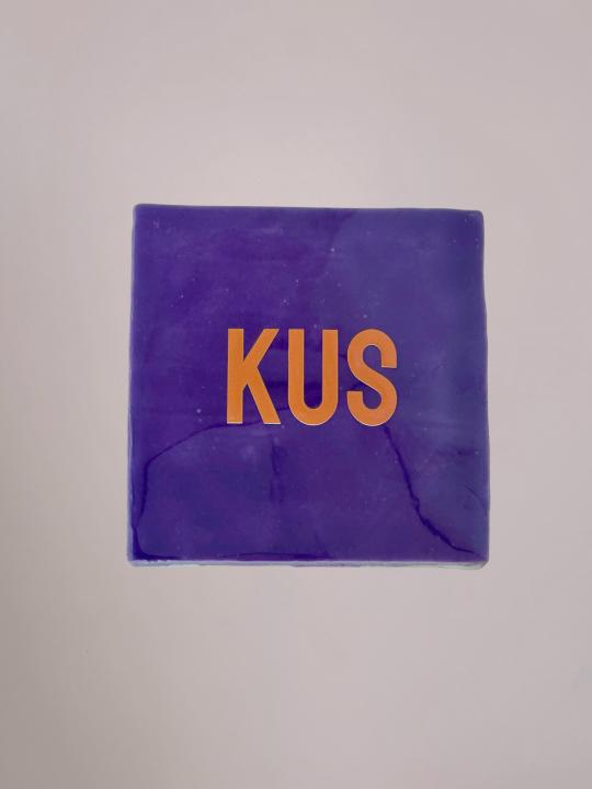 Paars Yett Agenturen tegeltje van 10x10 cm met de roze tekst 'KUS' en een glanzende afwerking. Een liefdevol decoratietegeltje.
