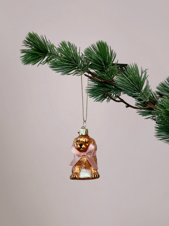 Glazen labradoodle kerstbal Vondels met mat goudblonde kleur en roze strik hangend in een kerstboom.