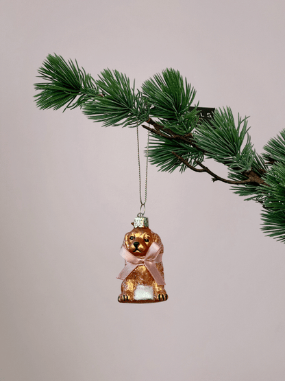 Glazen labradoodle kerstbal Vondels met mat goudblonde kleur en roze strik hangend in een kerstboom.
