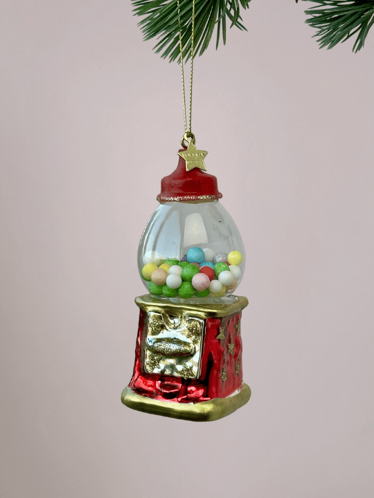 Close-up van Vondels rode kauwgumbalmachine kerstornament met gekleurde kauwgomballen en gouden randen op witte achtergrond.