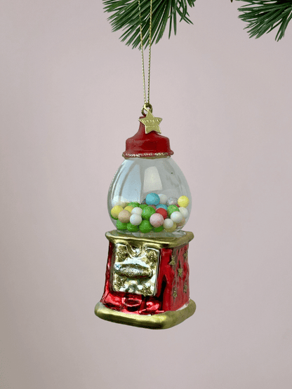 Close-up van Vondels rode kauwgumbalmachine kerstornament met gekleurde kauwgomballen en gouden randen op witte achtergrond.