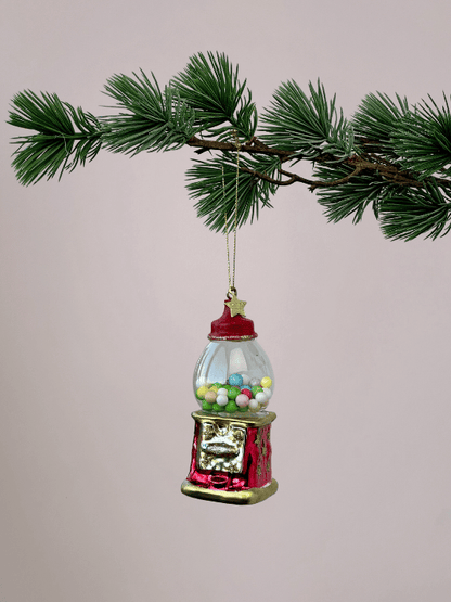 Rode kauwgumbalmachine kerstbal van Vondels met gekleurde kauwgomballen en gouden randen hangend in een kerstboom.