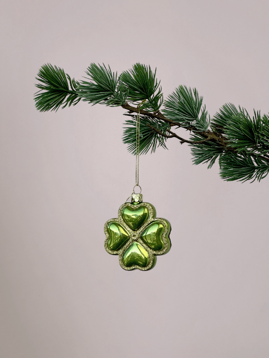 Vondels geluksornament groen klavertje vier met gouden glitterranden hangend in een kerstboom.