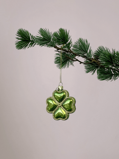Vondels geluksornament groen klavertje vier met gouden glitterranden hangend in een kerstboom.