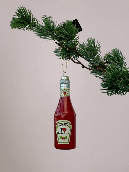 Vondels rode ketchupfles kerstbal met lange hals en zilveren glinsterende dop hangend in een kerstboom.