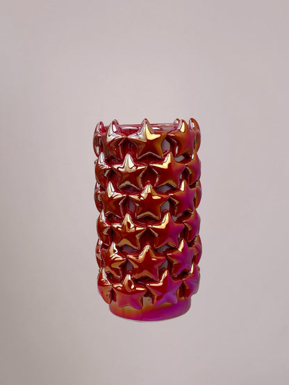 Kleine rode vaas van opzij, holografische glans varieert van roze, goud tot zilver, sterren zichtbaar op het oppervlak