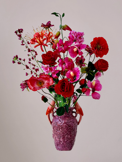 Roze vaas met oranje vogeltjes gevuld met een luxe Moederdag boeket van kunstbloemen in roze, rood en oranje tinten