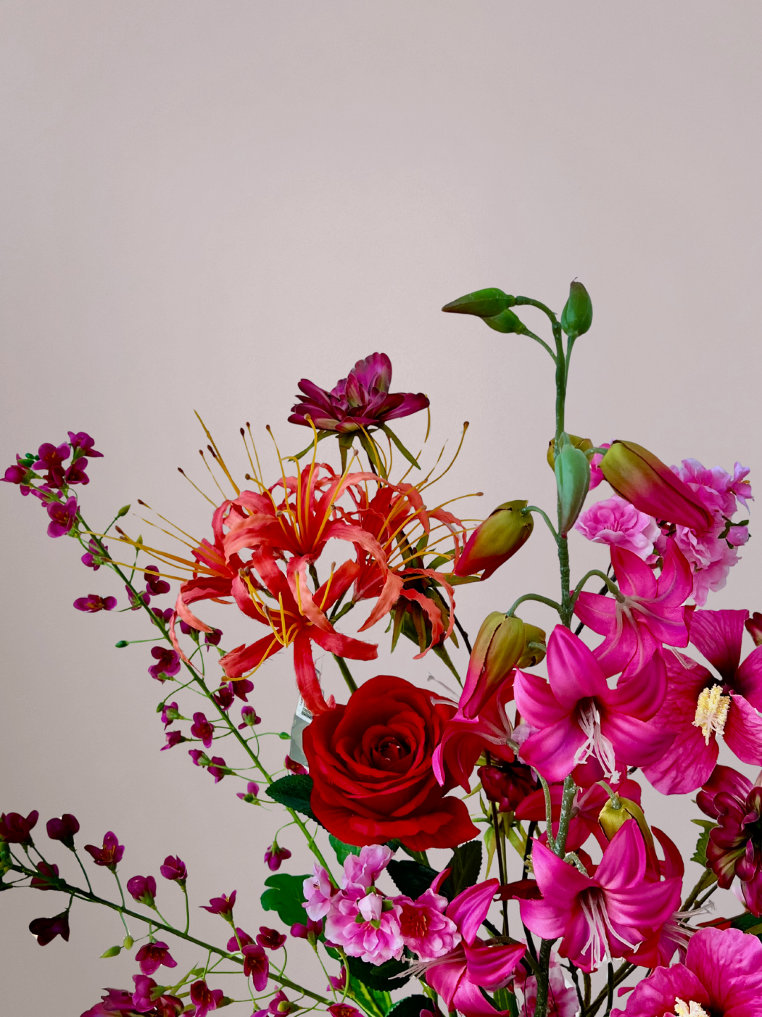 Roze vaas met oranje vogeltjes gevuld met een luxe Moederdag boeket van kunstbloemen in roze, rood en oranje tinten