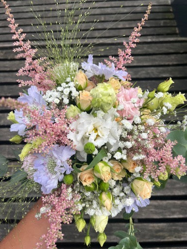 Bruidsboeket met pastelkleurige rozen en seizoensbloemen, stijlvol en handgebonden