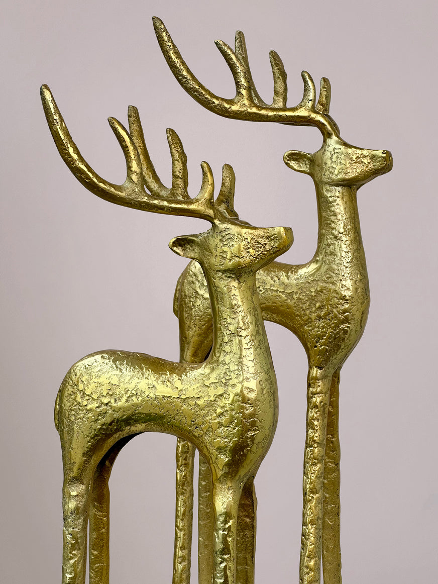 Close-up van gouden rendier met glanzende afwerking op lichtroze achtergrond, perfect als kerstdecoratie.