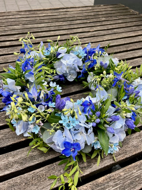 Detailfoto van rouwboeket hartvorm met witte, blauwe en paarse bloemen