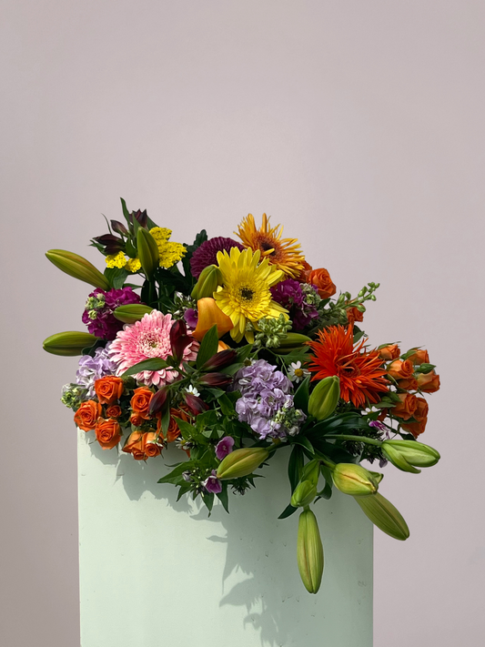 Kleurrijk rouwboeket met gemengde bloemen in roze, geel, paars en oranje tinten