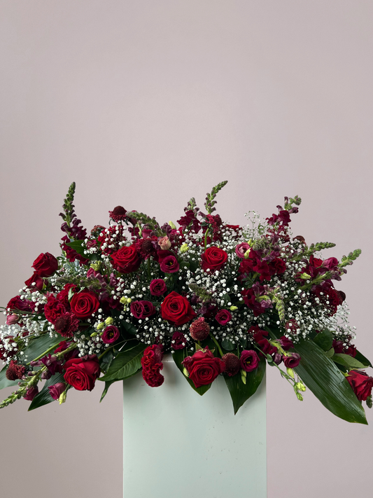 Rouwboeket rode rozen met wit gipskruid en fris groen als stijlvol bloemstuk voor een warm en liefdevol afscheid.