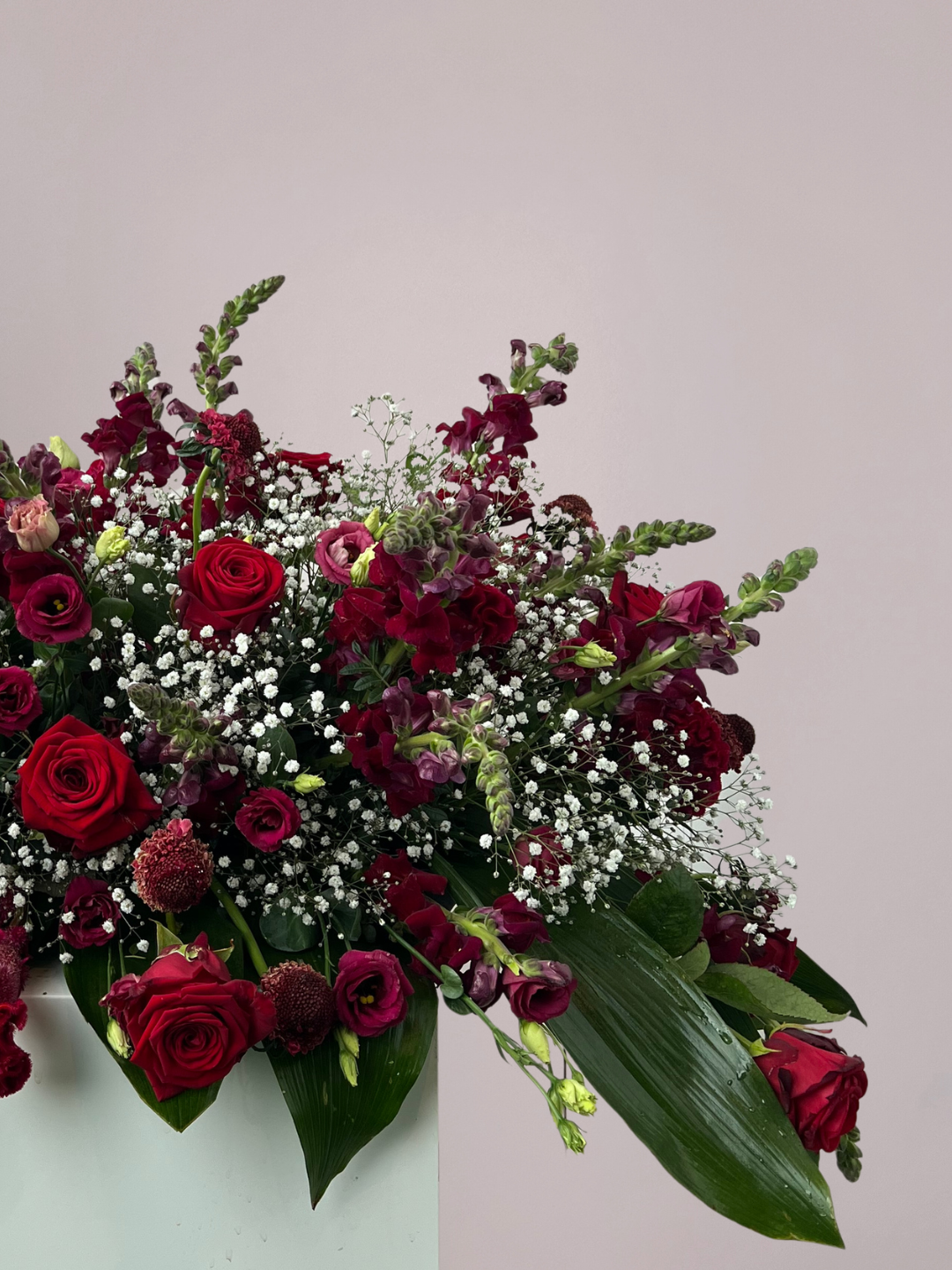 Alt-tekst afbeelding:
Rouwboeket rode rozen met wit gipskruid en fris groen als stijlvol bloemstuk voor een warm en liefdevol afscheid.