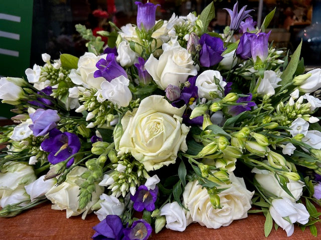 Rouwboeket witte rozen en veldbloemen in natuurlijke, losse stijl met diverse kleuren