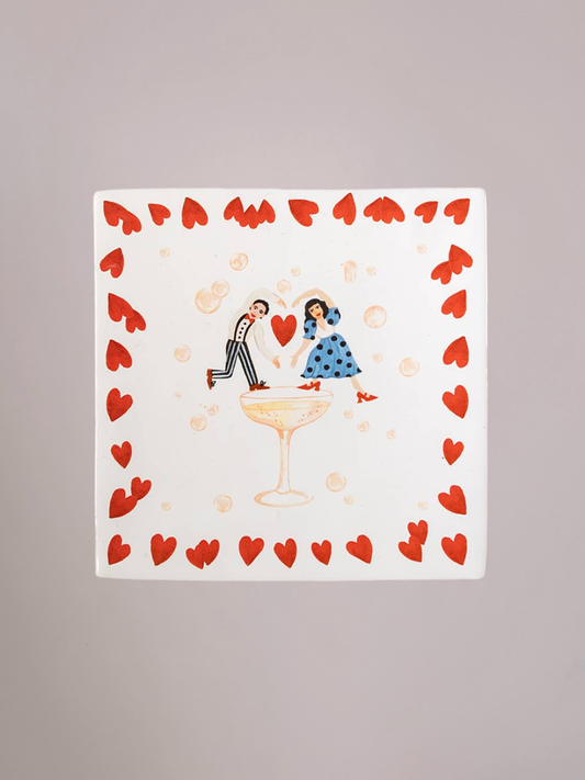 Delfts blauw StoryTiles tegeltje Proost op de liefde met twee figuren die samen het glas heffen, een sfeervolle illustratie die liefde, samenzijn en het vieren van bijzondere momenten uitbeeldt.