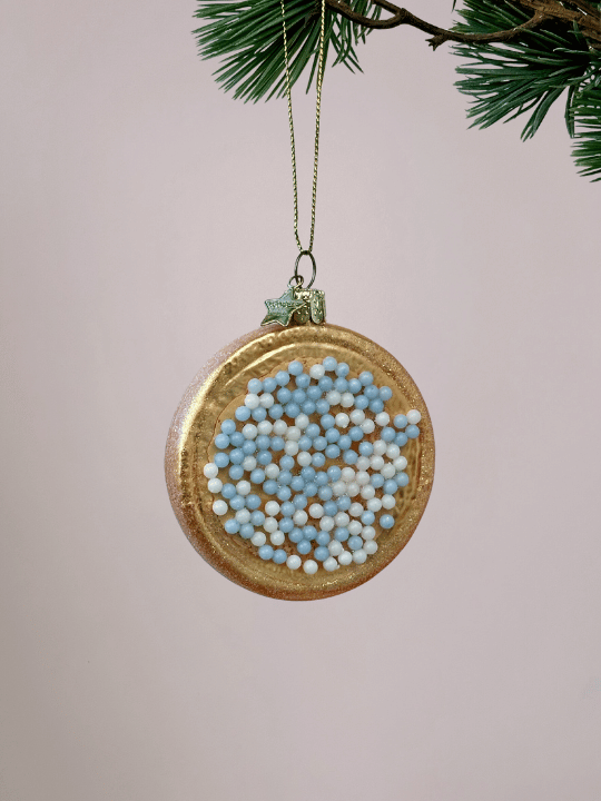 Close-up van beschuit met muisjes kerstornament Vondels in blauw en wit met glitterrandje op witte achtergrond.