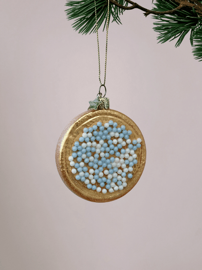 Close-up van beschuit met muisjes kerstornament Vondels in blauw en wit met glitterrandje op witte achtergrond.