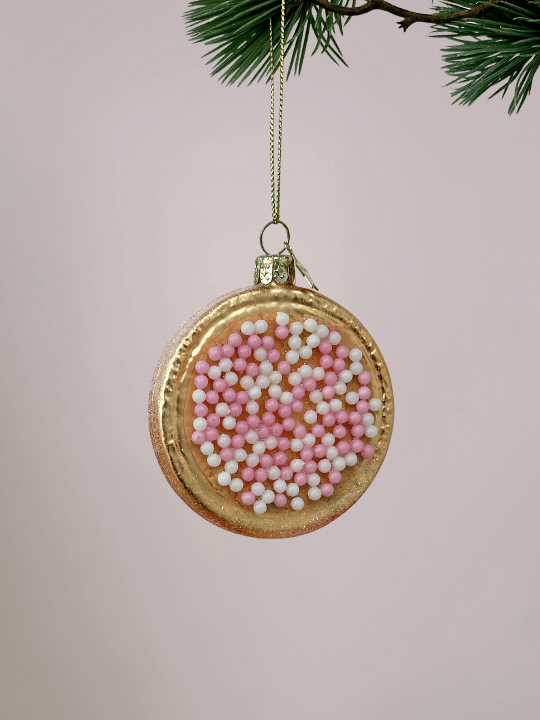 Vondels Roze beschuit met muisjes kerstornament met glinsterende rand op pastelroze achtergrond.