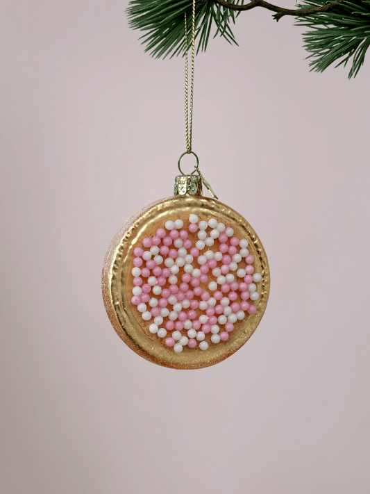 Vondels Roze beschuit met muisjes kerstornament met glinsterende rand op pastelroze achtergrond.
