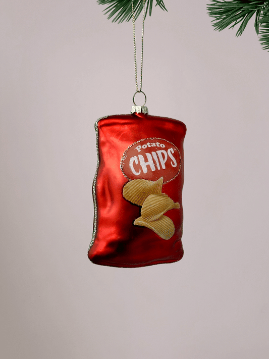 Close-up van rode chipszak kerstornament Vondels met de tekst ‘Potato Chips’ op lichtroze achtergrond.
