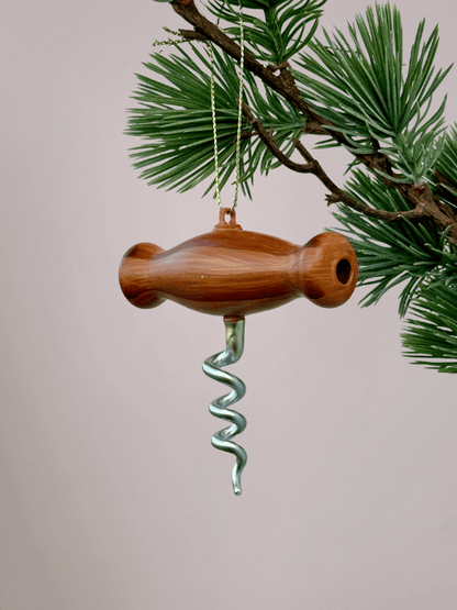 Vondels kurkentrekker kerstbal van glas met houten handvat, origineel ornament voor kerstboom en lichtroze achtergrond.