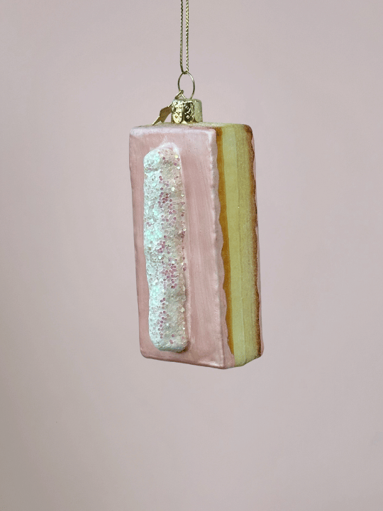 Close-up van roze tompouce kerstbal met vulling, witte streep slagroom en glitters, bijzondere kerstbal en Vondels kerstornament