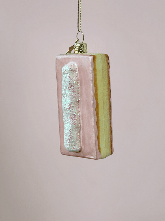 Close-up van roze tompouce kerstbal met vulling, witte streep slagroom en glitters, bijzondere kerstbal en Vondels kerstornament