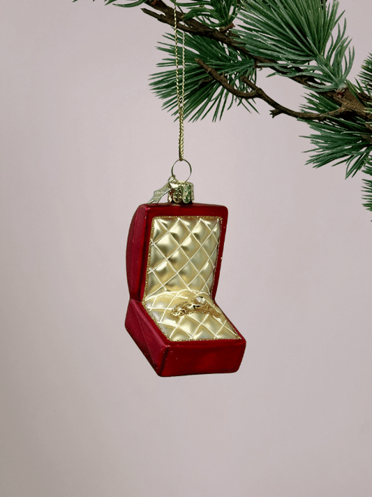 Close-up van Vondels rood doosje kerstornament met goudkleurig kussen en trouwring met diamant, glimmend en feestelijk ornament voor kerstboom